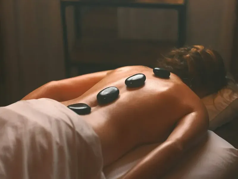 Mulher deitada com pedras quentes nas costas durante massagem em Curitiba.