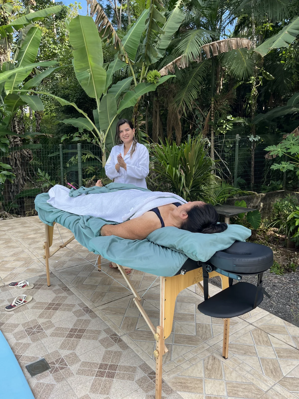 Ket realizando massagem ao ar livre em ambiente com natureza tropical — Excellence Ateliê